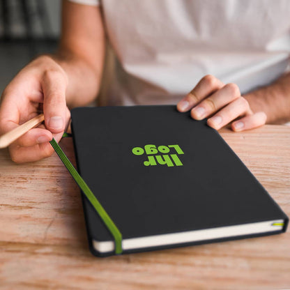 A5 Notizbuch wird geöffnet, zeigt farbige Lasergravur und hochwertigen Kunstlederumschlag