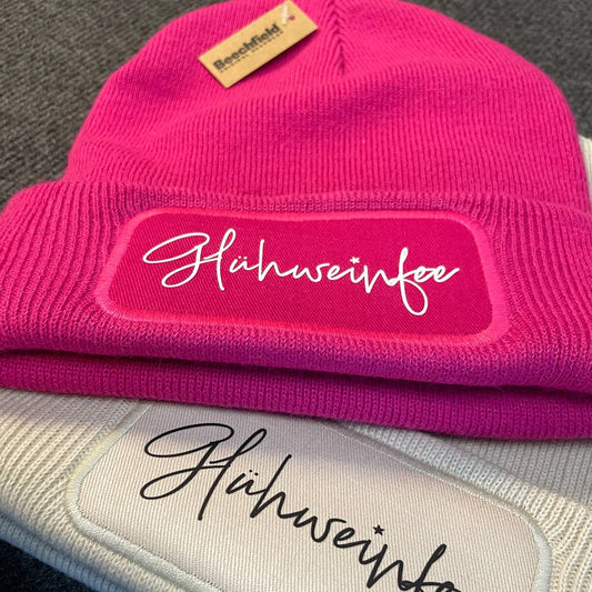 Zwei Wintermützen mit dem Motiv ‚Glühweinfee‘ im Großformat, perfekte Geschenkidee für die kalte Jahreszeit.