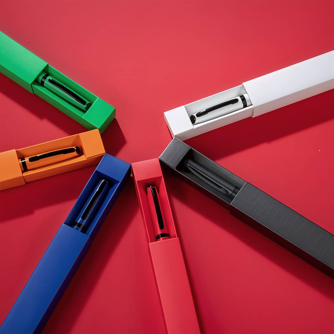 Alle Farbvarianten des gravierten Kugelschreibers Zeta – personalisierbar in Weiß, Anthrazit, Rot, Orange, Grün und Blau